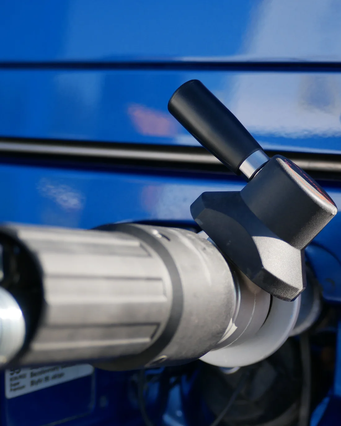 A CNG refuelling nozzle connected to a blue vehicle